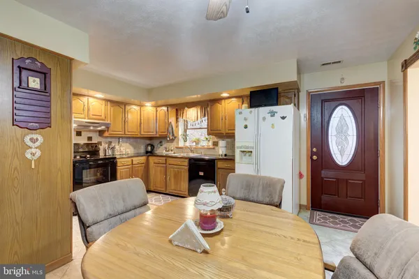 a living room with stainless steel appliances furniture a rug and a kitchen view