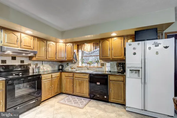 a kitchen with granite countertop a refrigerator stove top oven and sink
