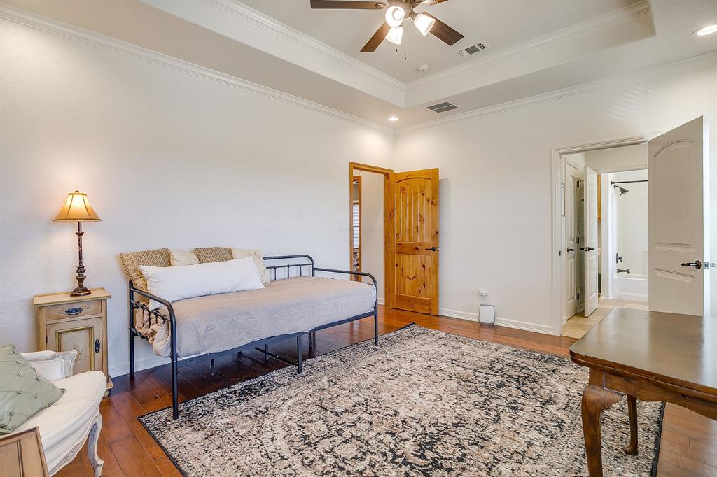 2608 Turkey Creek Road Mineral Wells, TX 76067 - Photo 28 of 39 a spacious bedroom with a bed a chandelier with the dresser and mirror