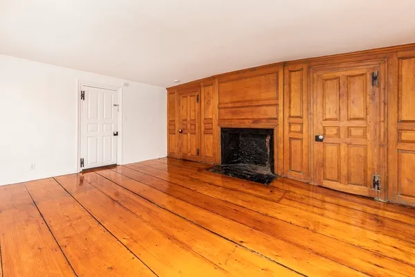 an empty room with wooden floor fireplace and windows