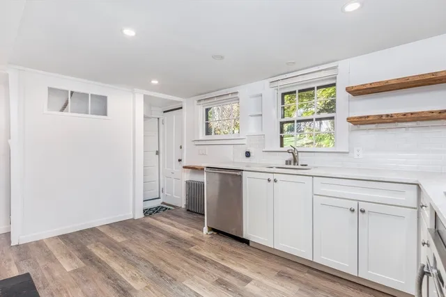 a view of a kitchen with white cabinets and wooden floor