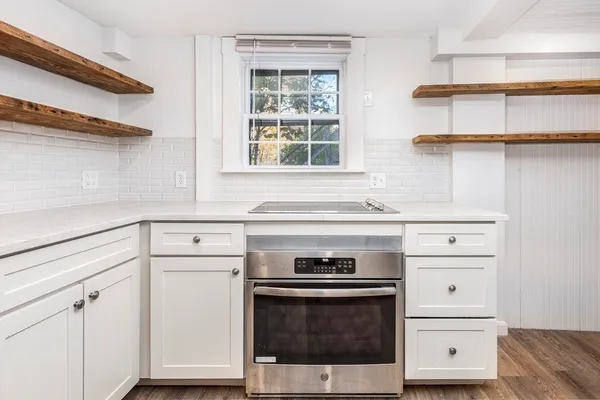 a kitchen with stainless steel appliances white cabinets and a wooden floor
