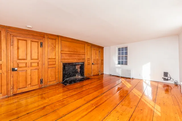 a view of empty room with wooden floor and fireplace