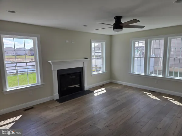 a view of an empty room with wooden floor fireplace and a window