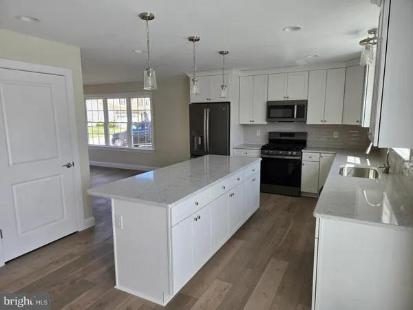 a kitchen with granite countertop a sink a counter space appliances and cabinets