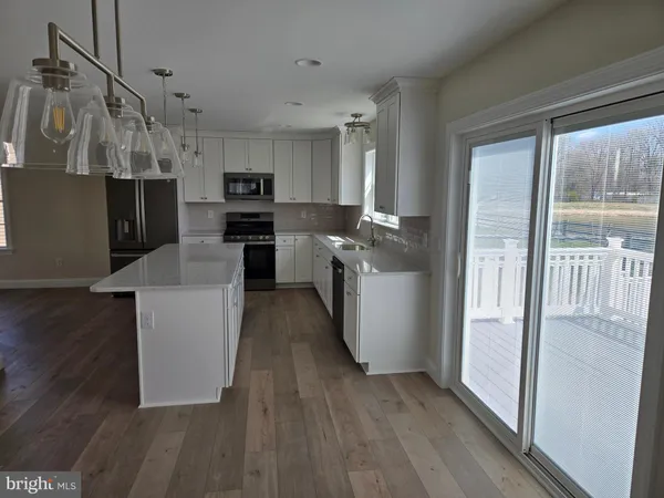 a kitchen with kitchen island wooden floors and stainless steel appliances