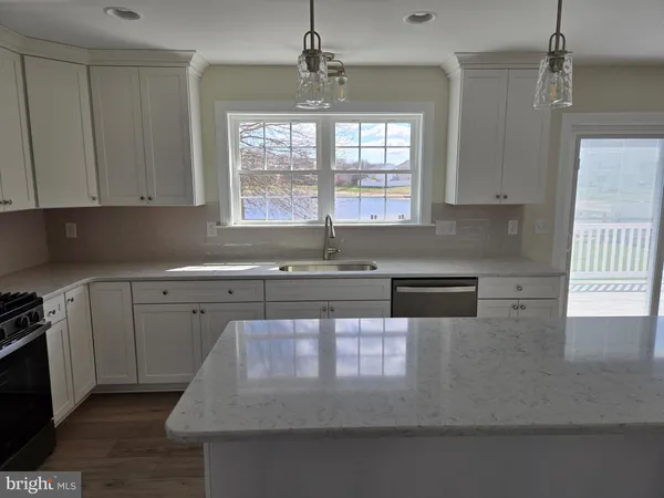 a kitchen with granite countertop a sink a window stainless steel appliances and cabinets