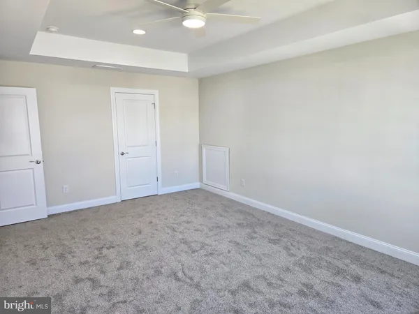 an empty room with a ceiling fan and carpet