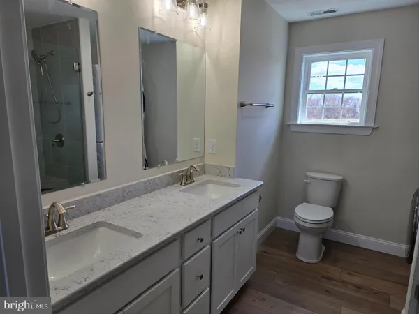 a bathroom with a granite countertop sink a toilet and a mirror