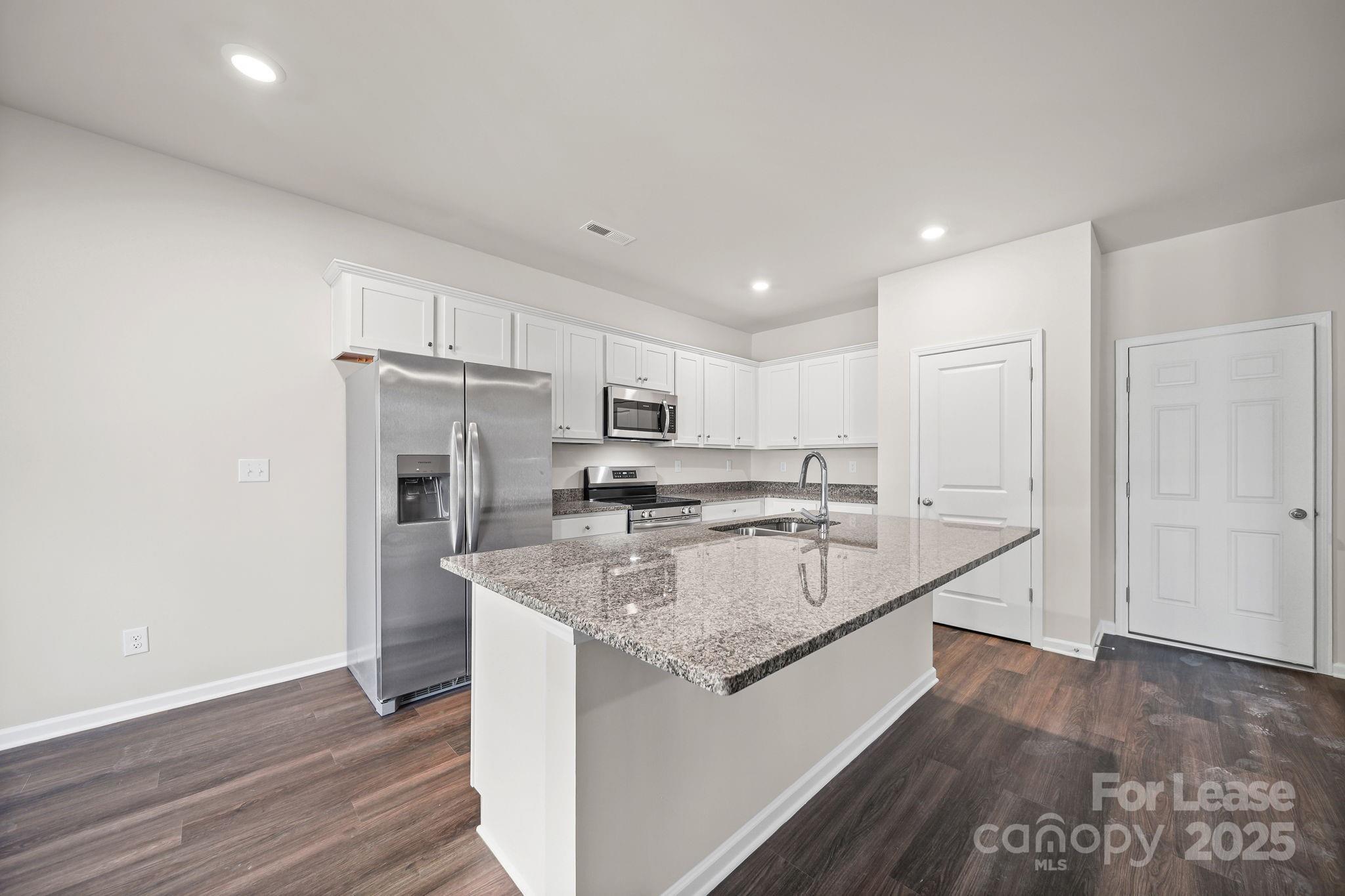 3200 Polk And White Road, Unit A Charlotte, NC 28269 - Photo 26 of 35 a large kitchen with a center island wooden floor and stainless steel appliances