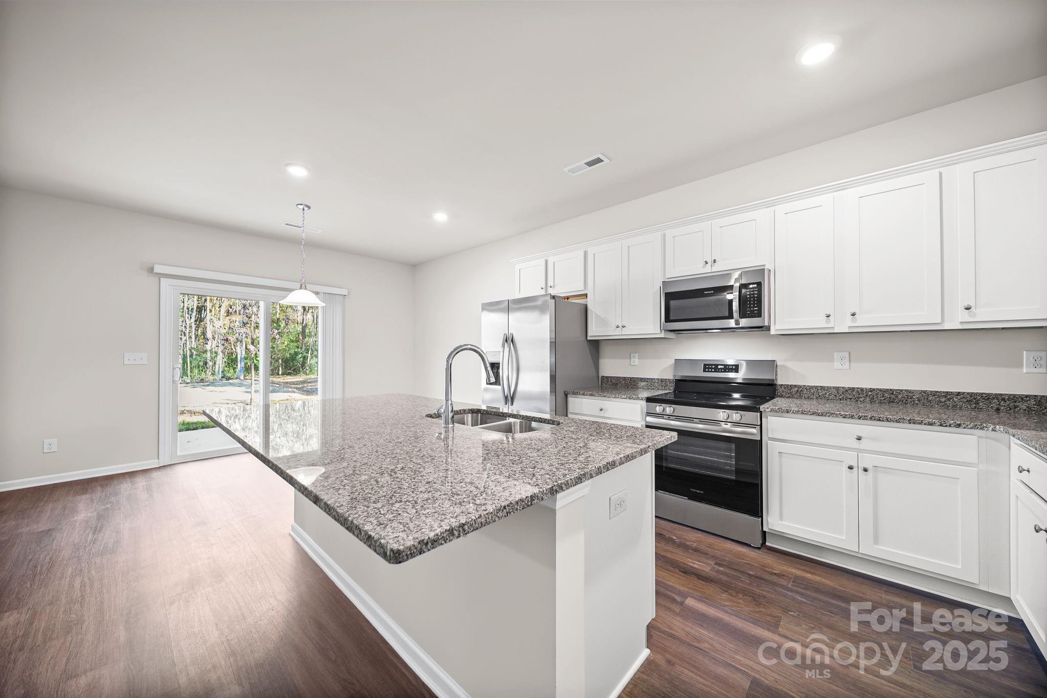 3200 Polk And White Road, Unit A Charlotte, NC 28269 - Photo 27 of 35 a kitchen with stainless steel appliances granite countertop a stove a sink a refrigerator white cabinets and wooden floor