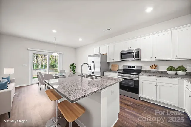 a kitchen with stainless steel appliances granite countertop stove top oven a sink dishwasher a dining table and chairs with wooden floor