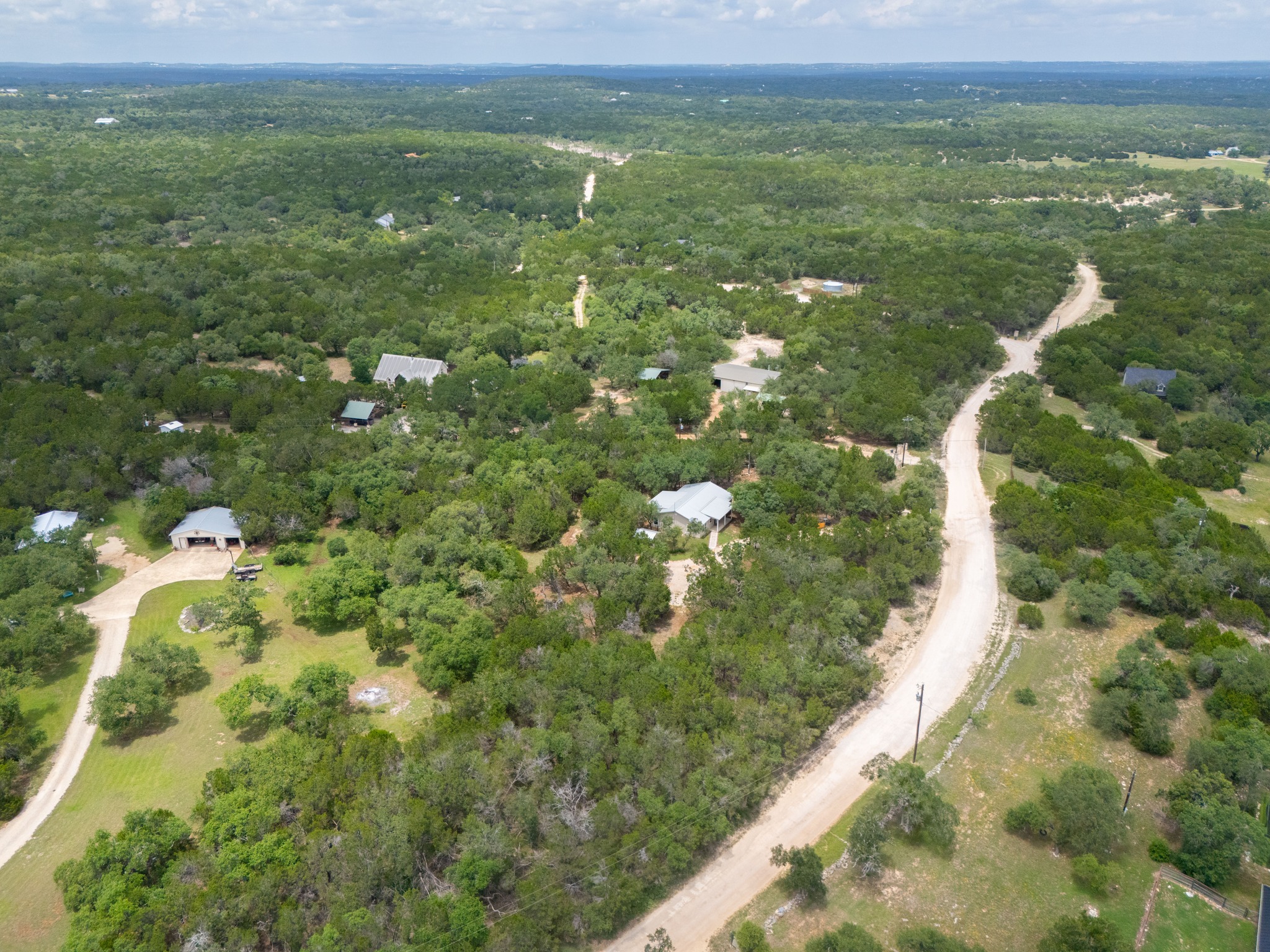 231 North Rainbow Ranch Road Wimberley, TX 78676 - Photo 36 of 40 Vast, verdant landscape offering a tranquil escape with scattered residences and winding unpaved roads.