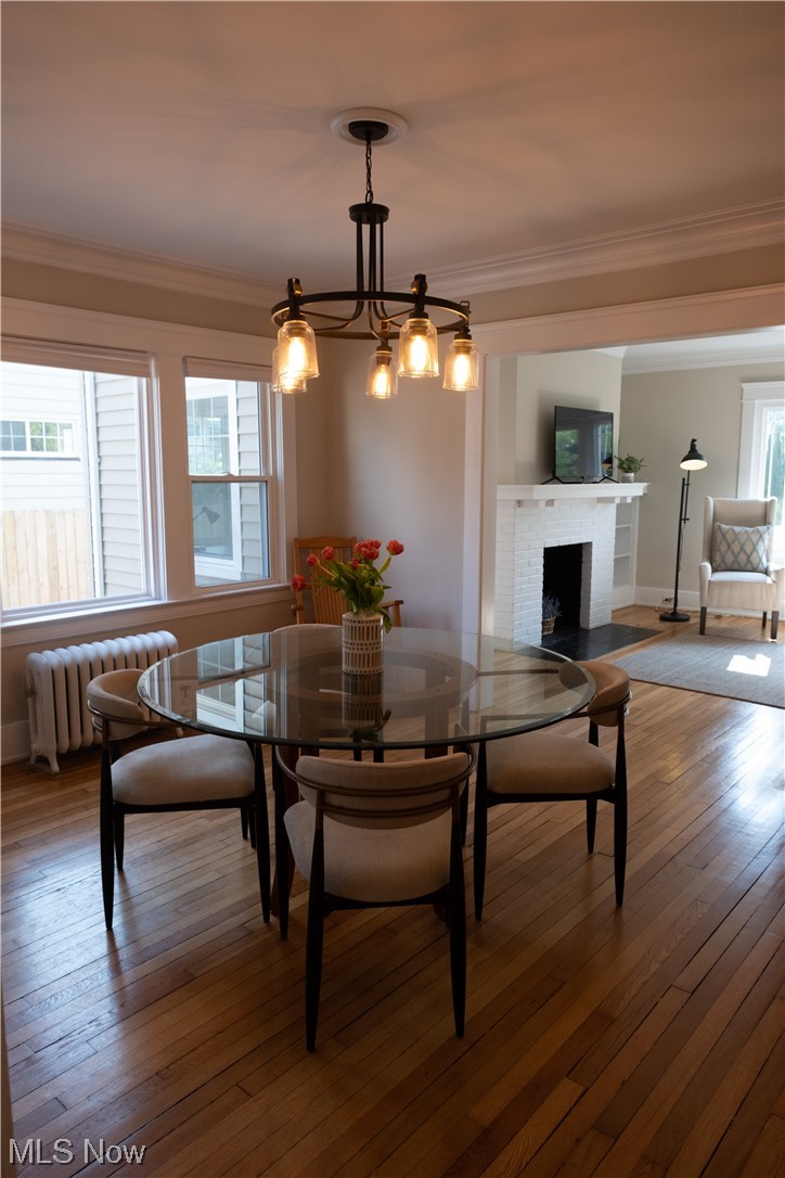 2135 Renrock Road Cleveland, OH 44118 - Photo 8 of 44 Dining area featuring radiator, a notable chandelier, crown molding, dark hardwood / wood-style floors, and a fireplace