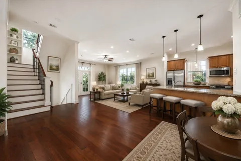 a living room with furniture kitchen view and a wooden floor