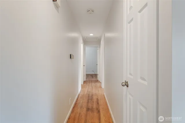a view of a hallway with wooden floor and a bathroom