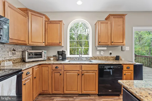 a kitchen with granite countertop a stove a sink dishwasher and cabinets with wooden floor