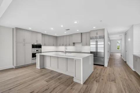 a large kitchen with stainless steel appliances a large counter top a sink and a refrigerator