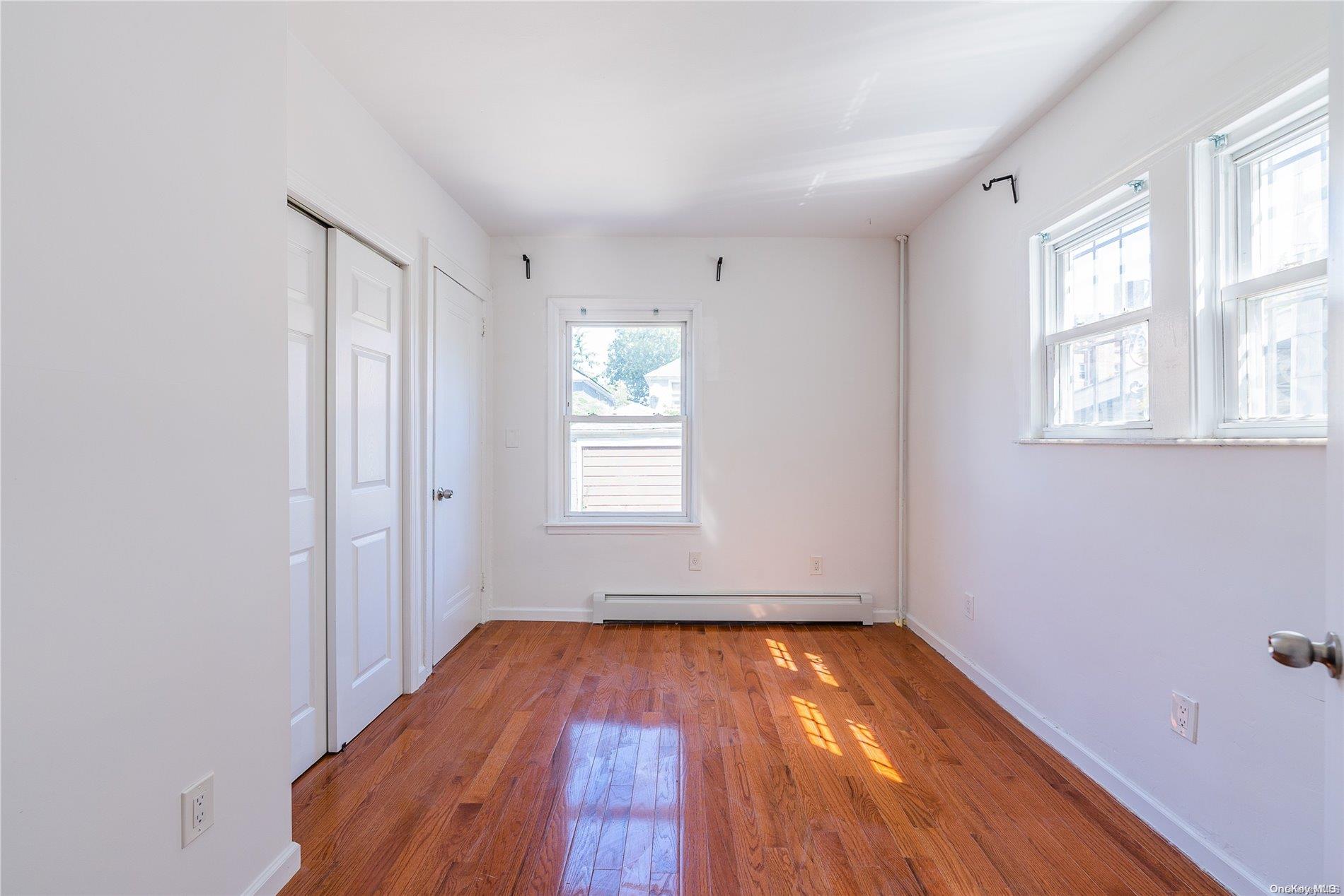 55-15 96th Street Queens, NY 11368 - Photo 11 of 31 an empty room with wooden floor and windows