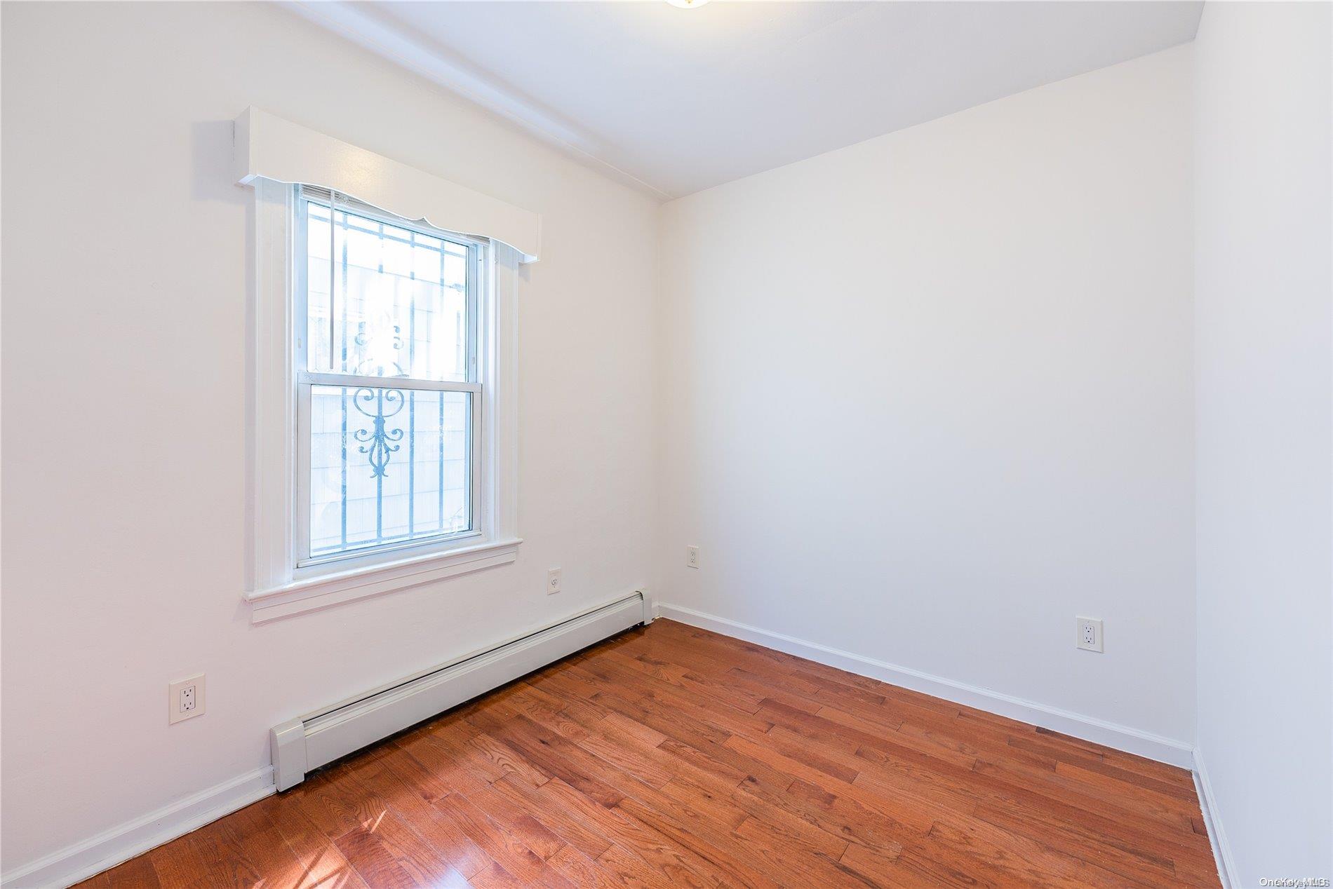 55-15 96th Street Queens, NY 11368 - Photo 13 of 31 an empty room with wooden floor and windows