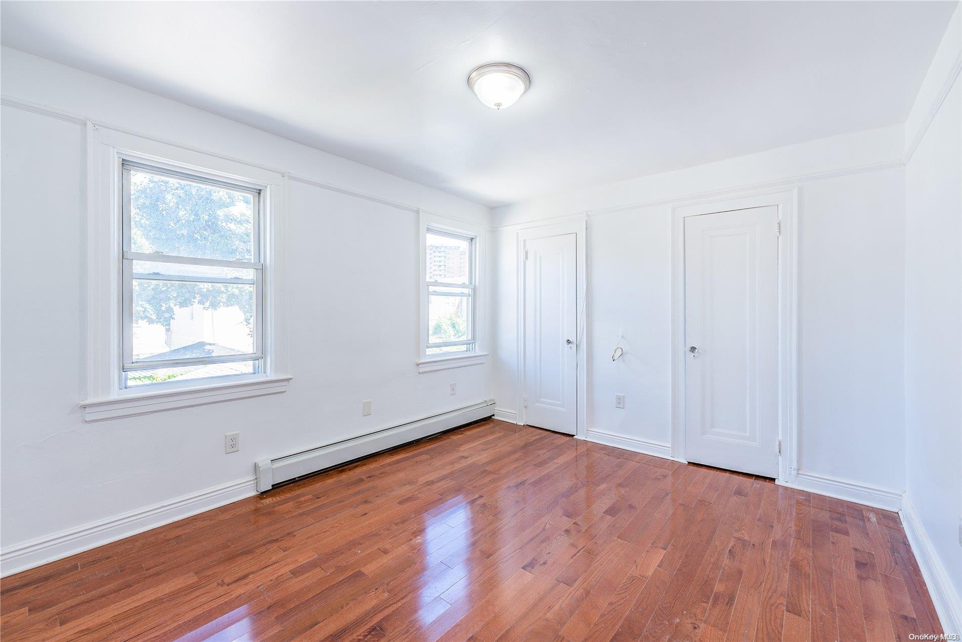 55-15 96th Street Queens, NY 11368 - Photo 19 of 31 an empty room with wooden floor and windows