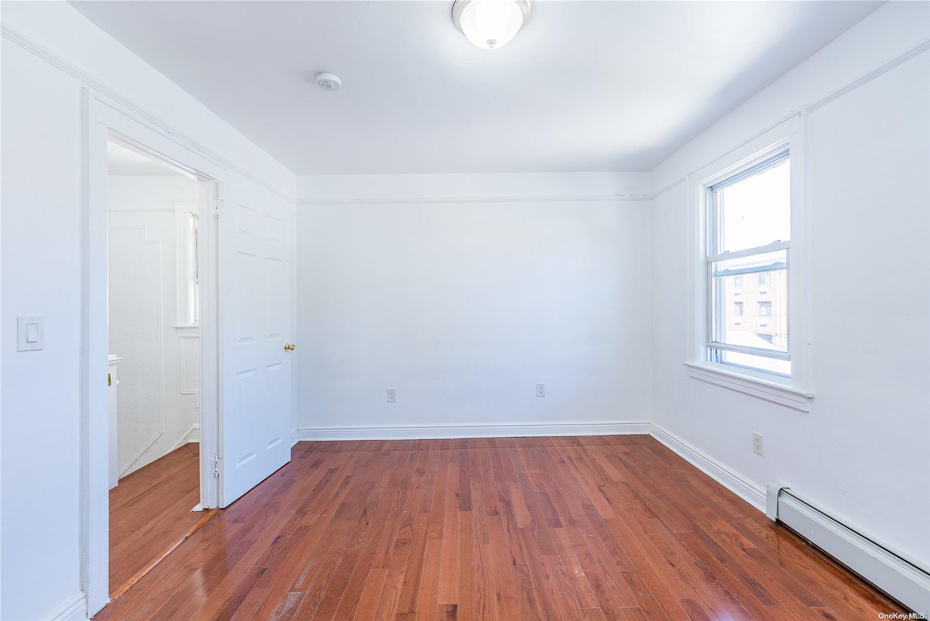 55-15 96th Street Queens, NY 11368 - Photo 20 of 31 an empty room with wooden floor and windows