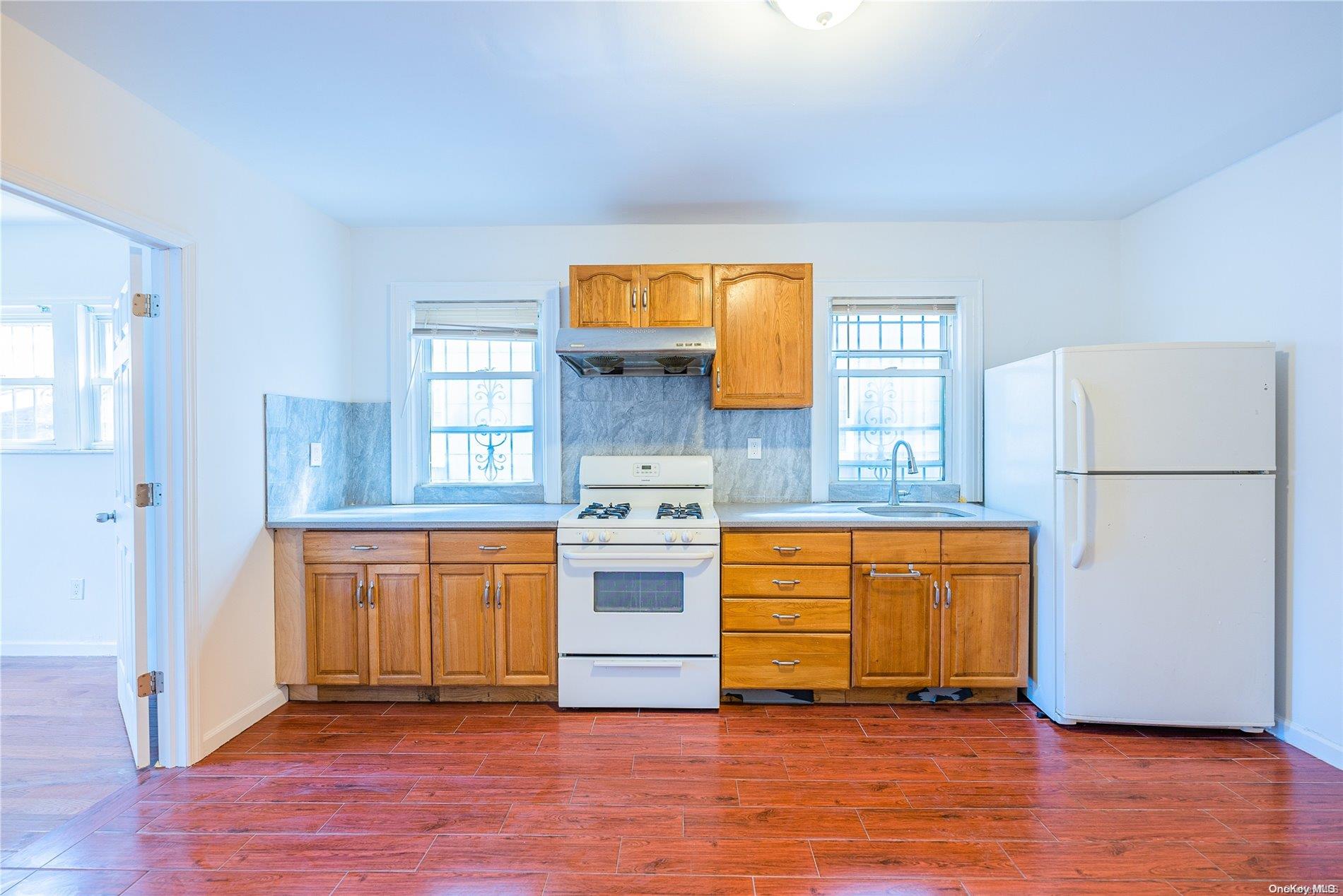 55-15 96th Street Queens, NY 11368 - Photo 9 of 31 a kitchen with granite countertop wooden floors and white stainless steel appliances