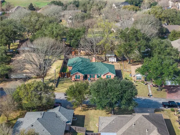 an aerial view of residential houses with outdoor space and trees