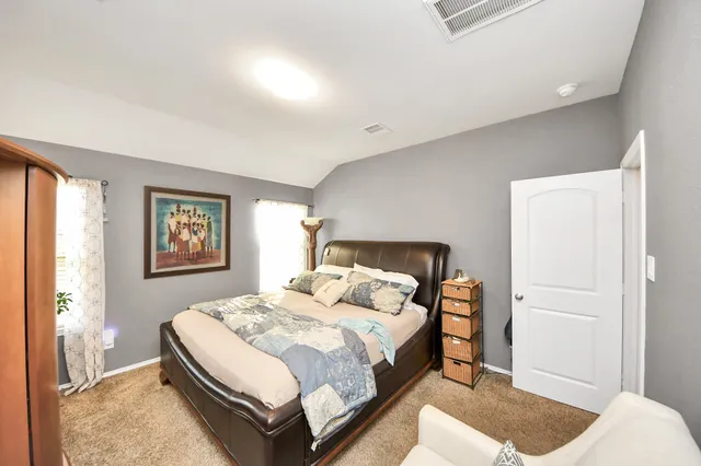 a spacious bedroom with a bed and a dresser in it