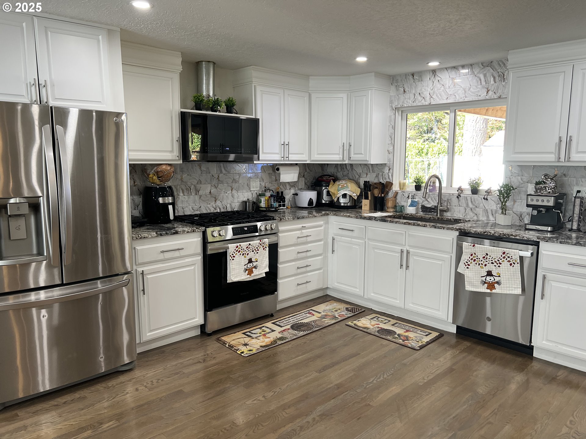 17519 Southeast Tibbetts Street Portland, OR 97236 - Photo 10 of 32 a kitchen with white cabinets stainless steel appliances and a window