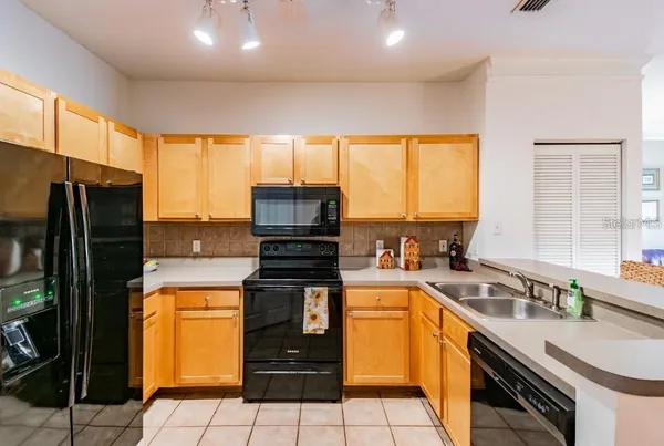 a kitchen with stainless steel appliances a sink a stove a refrigerator cabinets and a window