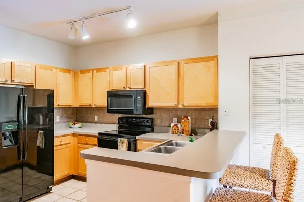a kitchen with stainless steel appliances a sink a stove a refrigerator cabinets and a large window