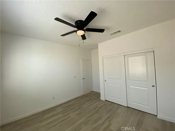 an empty room with wooden floor and a ceiling fan