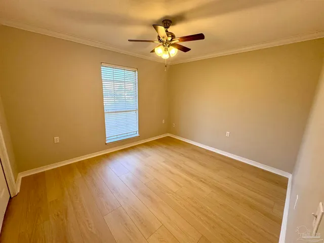 an empty room with wooden floor and fan