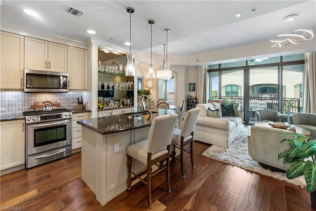 9115 Strada Place, Unit 5501 Naples, FL 34108 - Photo 8 of 31 a kitchen with stainless steel appliances granite countertop a stove and a wooden floors