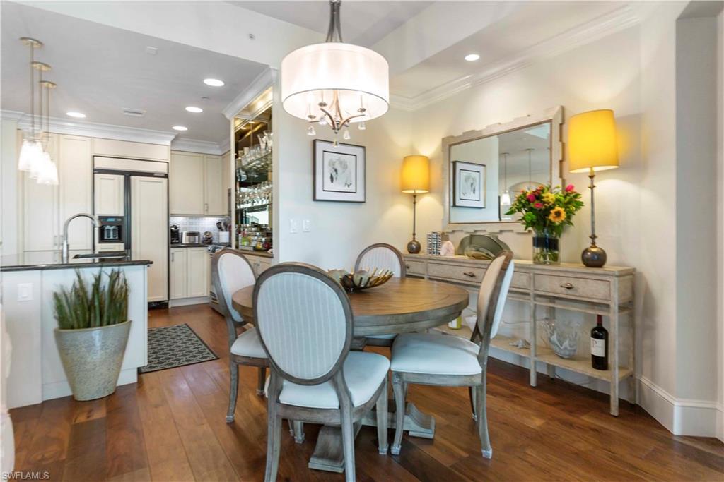 9115 Strada Place, Unit 5501 Naples, FL 34108 - Photo 9 of 31 a dining room with wooden floor a chandelier a glass table and chairs