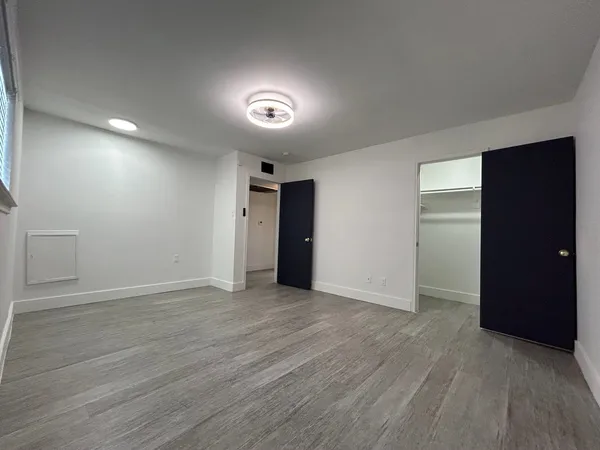 an empty room with wooden floor & closet and windows