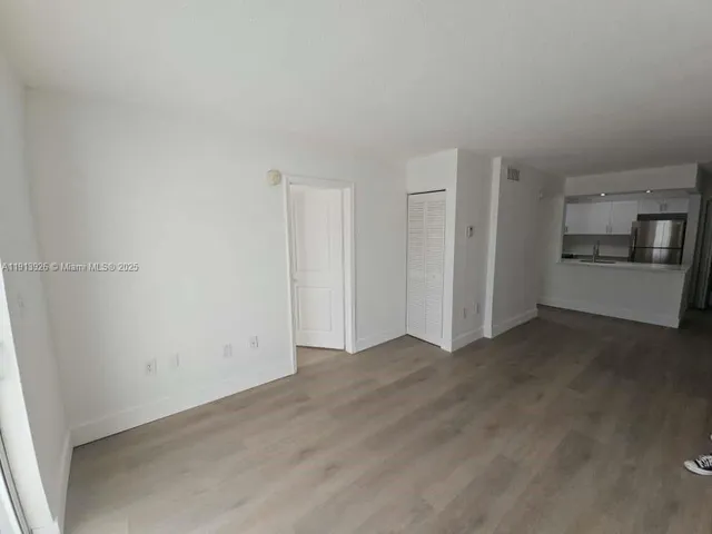 a view of a kitchen with refrigerator and white wall