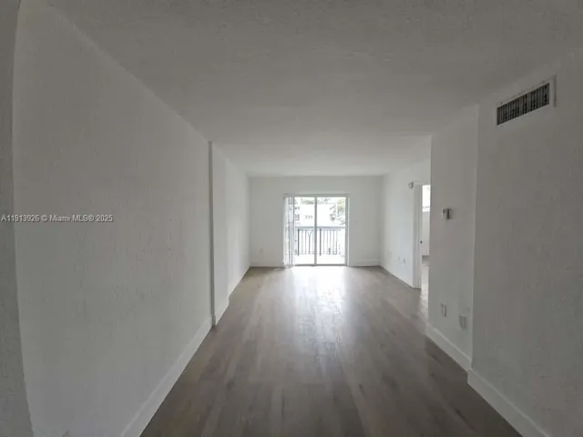 a view of empty room with window and wooden floor