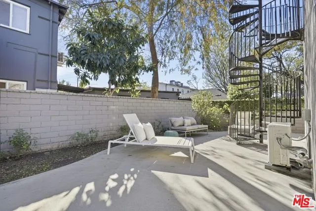 a view of a patio with couches and table and chairs with wooden fence and plants