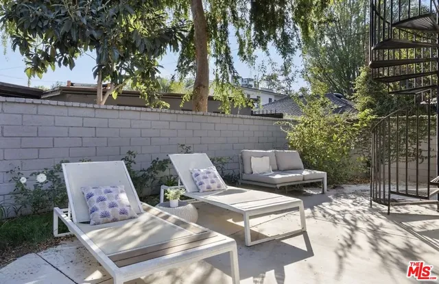 a view of a patio with table and chairs with wooden fence and large trees