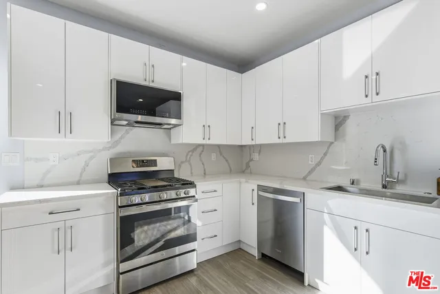 a kitchen with white cabinets and stainless steel appliances