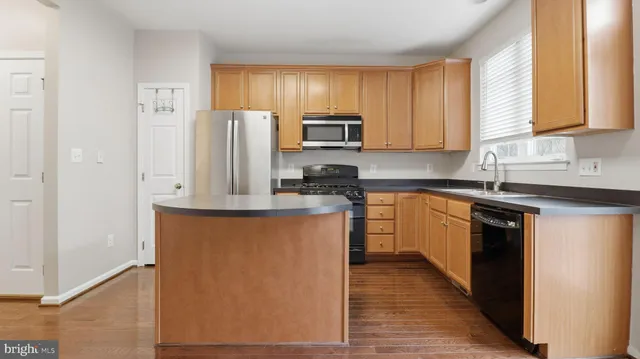 a kitchen with stainless steel appliances granite countertop a refrigerator a sink dishwasher a stove and a refrigerator with wooden floor