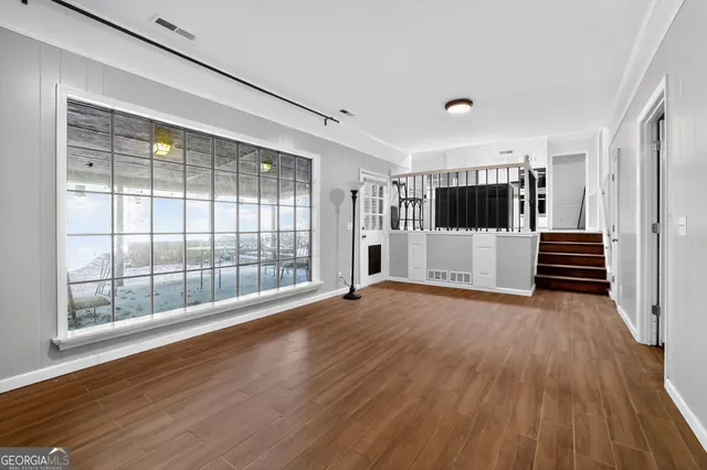 a view of empty room with wooden floor and windows