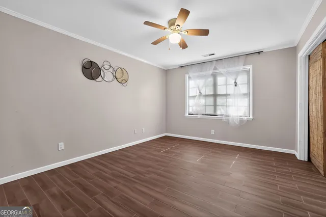 an empty room with wooden floor chandelier fan and windows