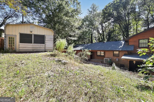 a backyard of a house with table and chairs under an umbrella