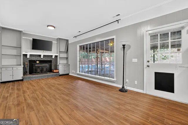 an empty room with windows fireplace and wooden floor
