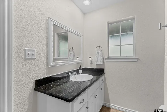 a bathroom with a granite countertop sink and a mirror