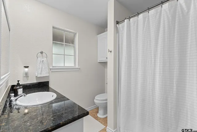 a bathroom with a granite countertop sink and a mirror