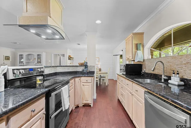 a kitchen with stainless steel appliances granite countertop a sink a stove and a wooden floors